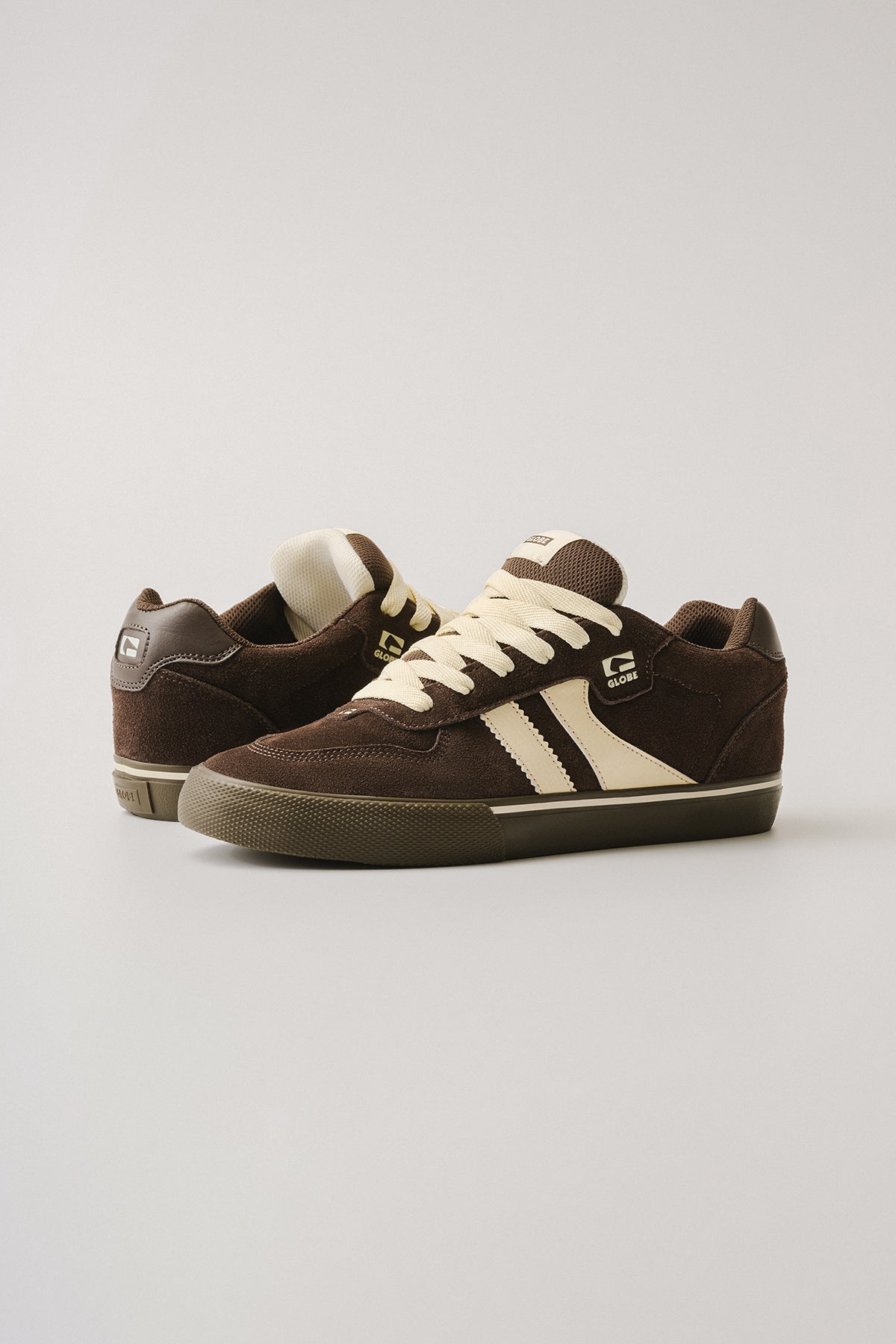 The Encore-2 - Brown/Dark Gum sneakers feature brown suede, cream laces and side stripes, with the Globe logo on the tongue and side, set against a plain light background.