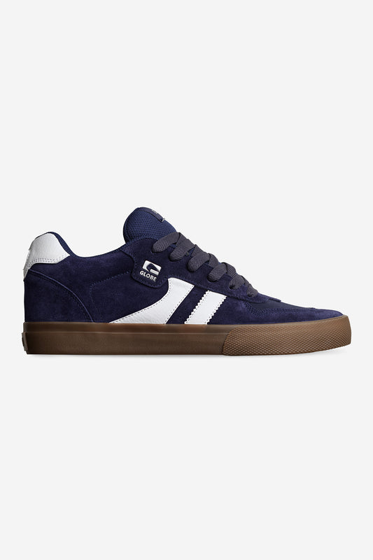 The Encore-2 - Maritime Blue is a navy blue suede sneaker with white accents, twin design stripes, a side logo, dark laces, and a brown vulcanized rubber sole, shown in side profile against a plain white background.