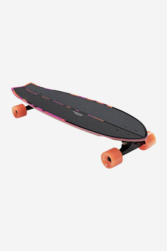 The Chromantic Cruiserboard 33" - Sea Devil is a black swallow-tail longboard with bright orange wheels and pink deck edge accents, displayed on a white background. Made from Resin-7 hard rock maple for a surf-inspired cruiser ride.