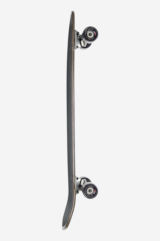 A vertical side view of the Blazer XL Longboard 36" - Flow, featuring a black grip tape surface, silver trucks, and black wheels, set against a plain white background.