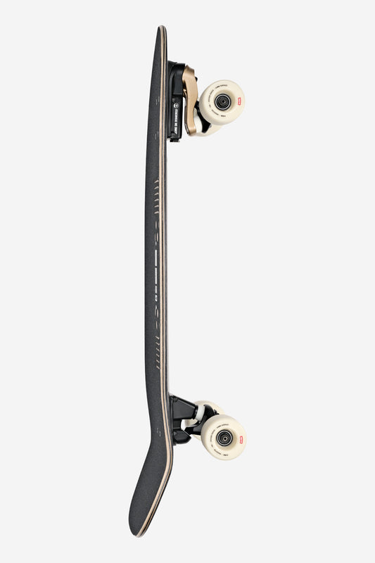 The Walrus Surf Skate Board 31" in Black/Peaking stands vertically on its side against a white background, featuring a textured grip deck with a slight upward curve and cream-colored wheels.