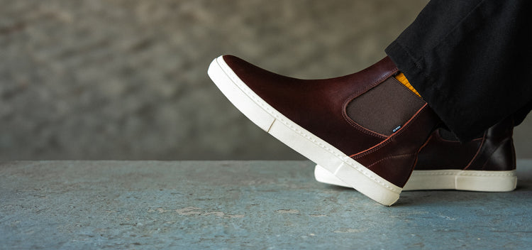 Brown slip-on shoes with white soles on a gray surface