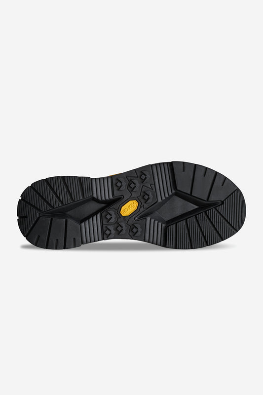 The image shows the black rubber Vibram sole of the DOVER-2000 - Black/Black, featuring deep angular treads, grooves, and a yellow hexagonal Vibram logo—ideal for rugged Chelsea boots in crazy horse leather.