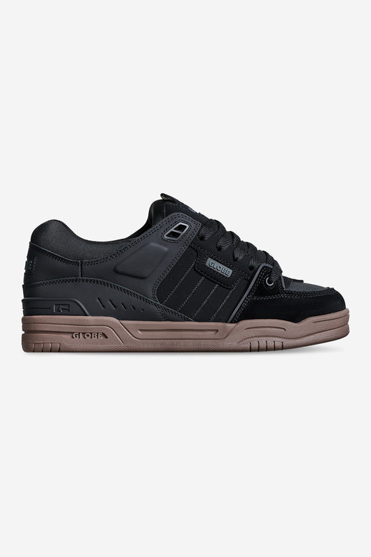 The Fusion - Black/Tobacco Gum is a black low-top sneaker featuring black laces, subtle stripe details, and a thick tobacco gum sole. Its sporty yet casual design makes it ideal for everyday wear.