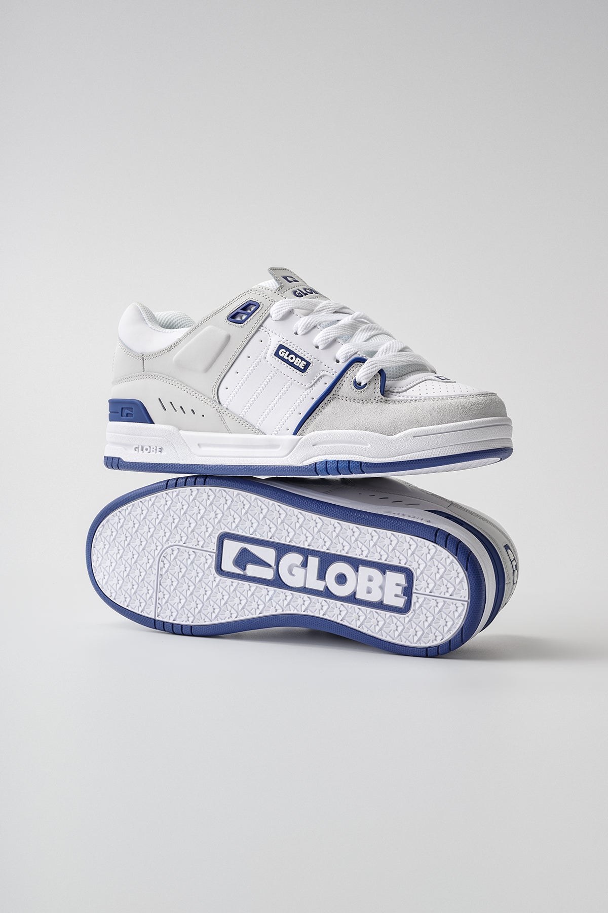 A pair of Globe Fusion skate shoes in blue and white, with one upright and the other on its side showcasing the sole and Globe logo, set against a plain light gray background.