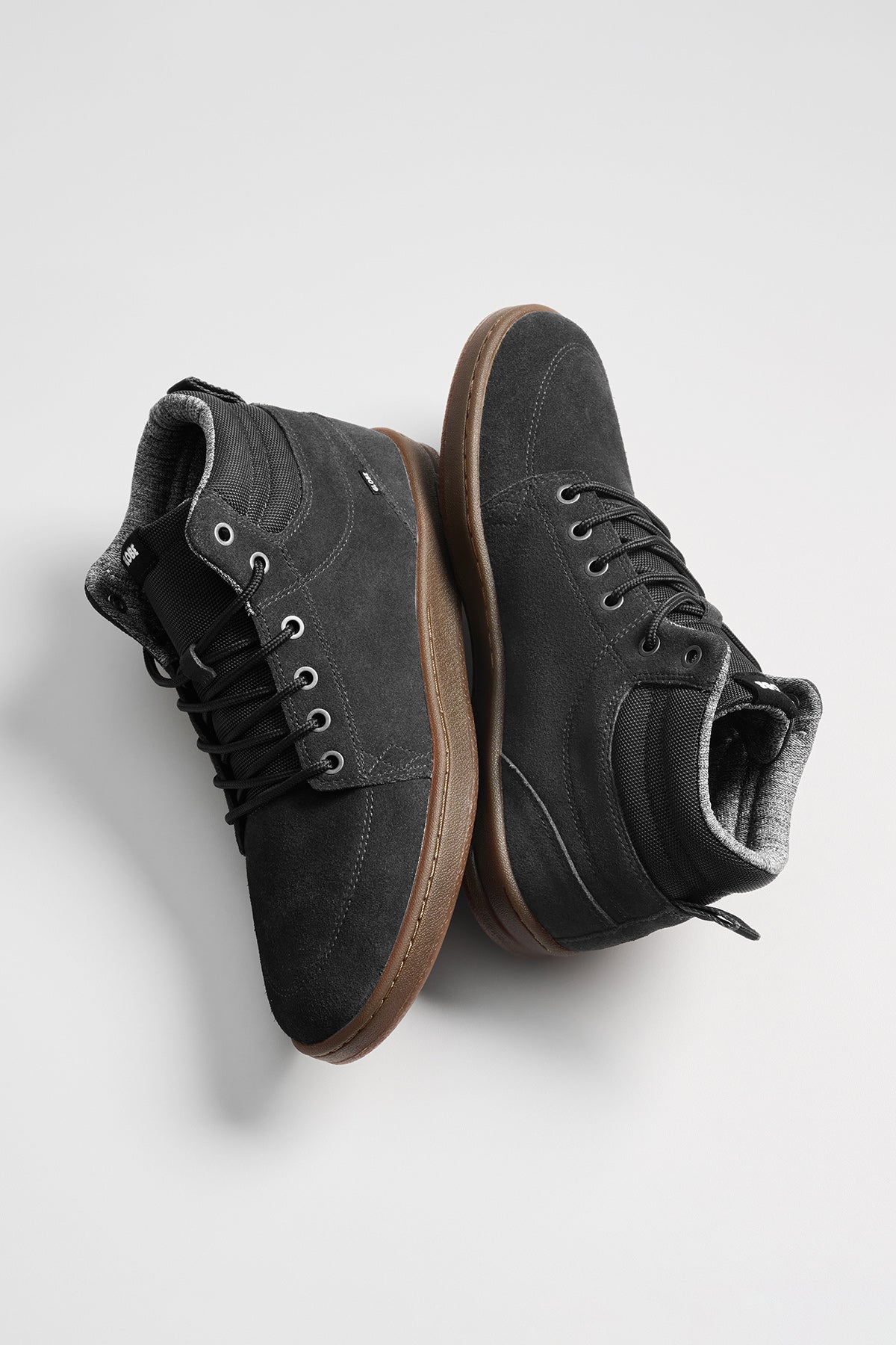 The GS Boot is a pair of black hi-top cup-sole sneakers in oiled suede, featuring brown rubber soles and black laces, shown against a plain light background.