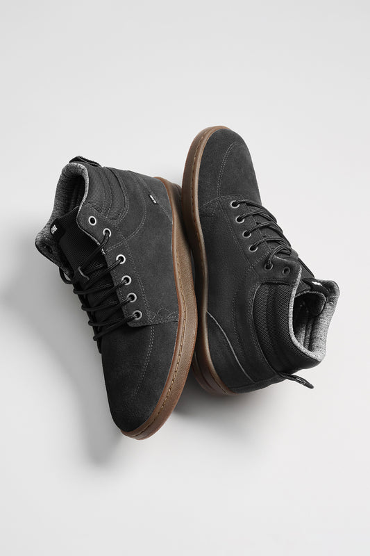 The GS Boot is a pair of black hi-top cup-sole sneakers in oiled suede, featuring brown rubber soles and black laces, shown against a plain light background.
