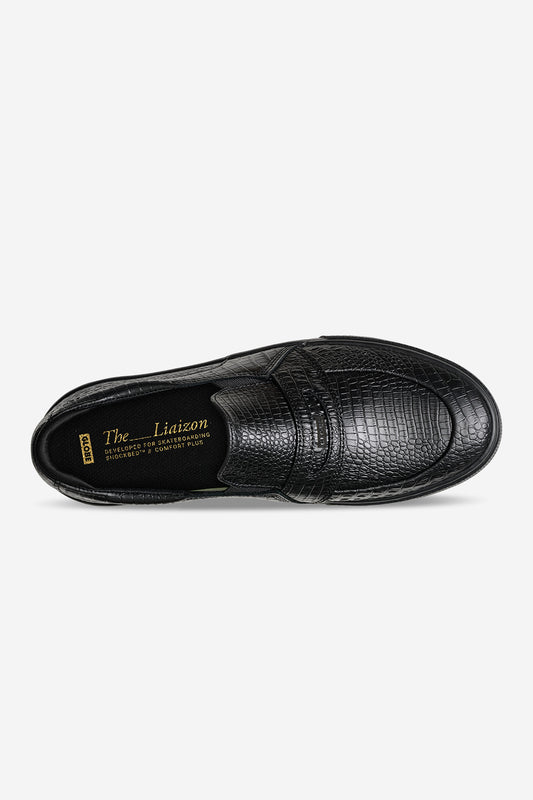 Top view of black crocodile embossed slip-on showing textured upper and strap detail