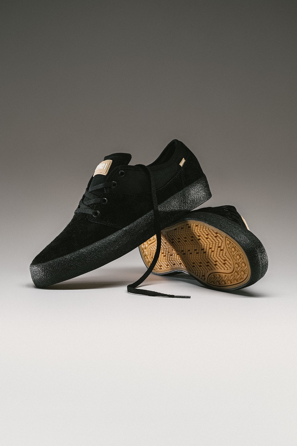 Pair of black Mahalo skate shoes arranged on a gray gradient background with visible gum sole