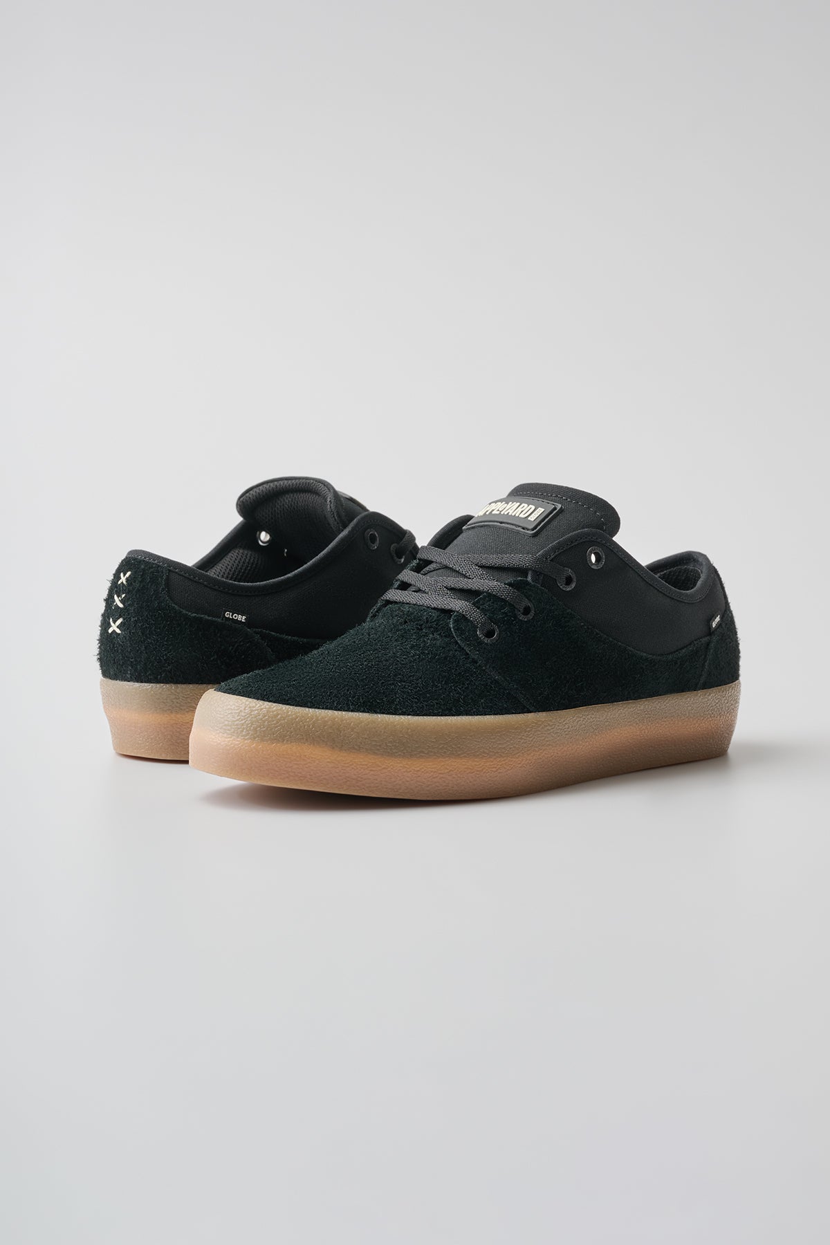 The Mahalo - Black/Gum/Crepe sneakers are shown on a plain light gray background, with one low-top black shoe facing forward and the other turned to display the gum crepe heel.