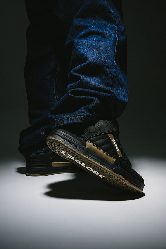 Tilt Black/Granite skate shoe on a denim-clad foot showing a molded collar and textured tread