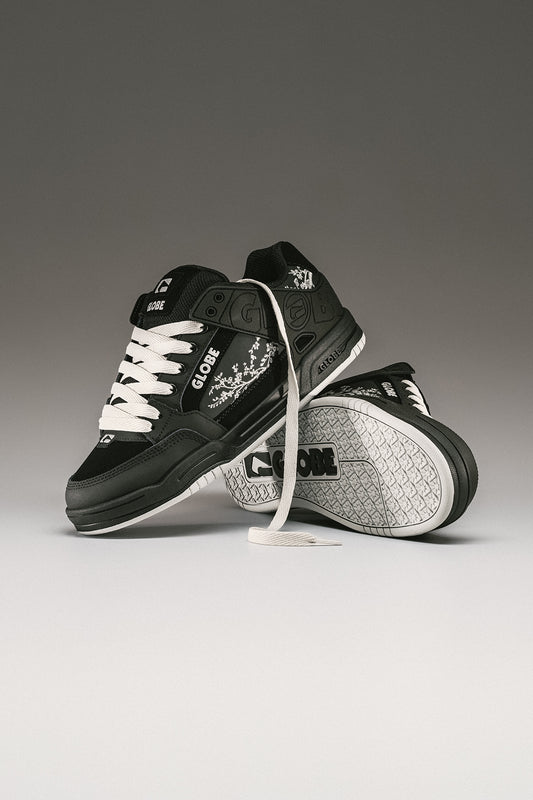 Studio shot of Tilt black Cherry Blossom sneakers with white laces and floral embroidery