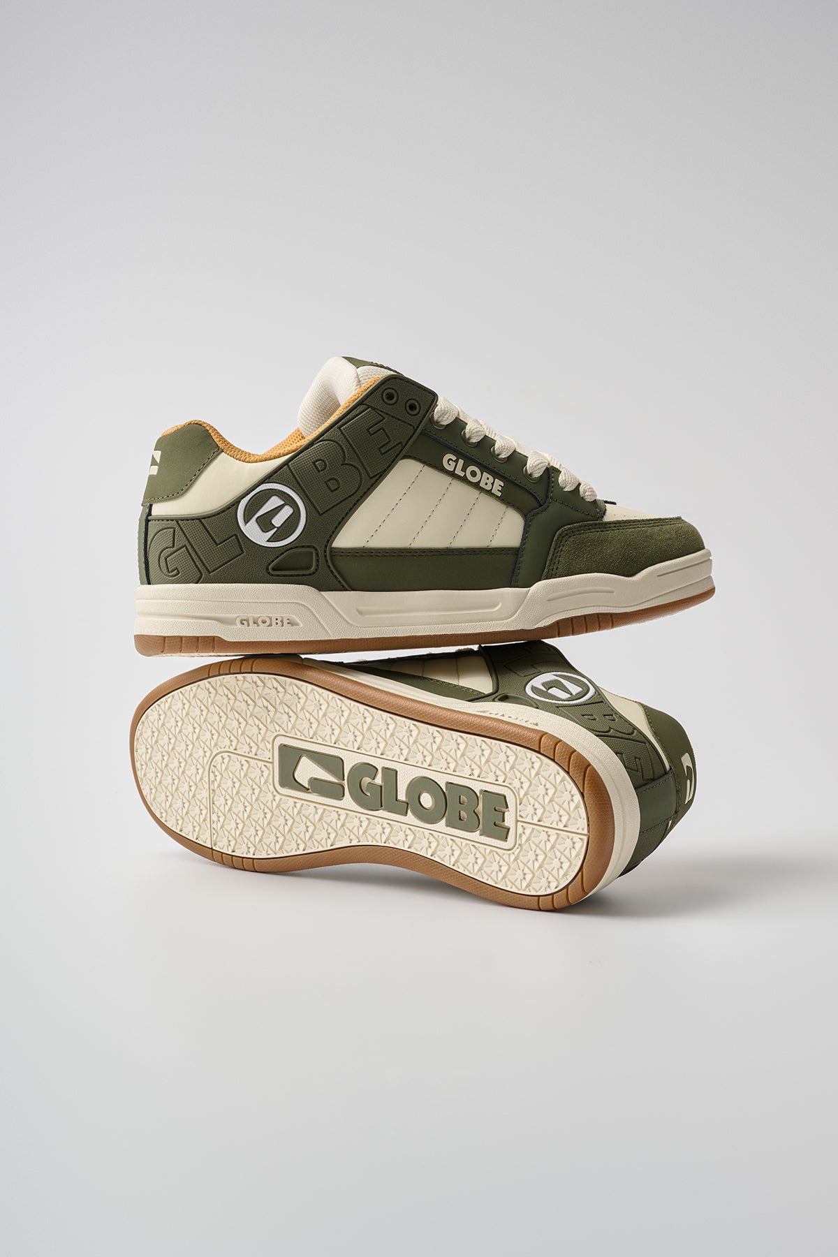 A pair of Tilt - Green/Antique Globe skate shoes, one upright and the other on its side atop it, feature the brand logo on the side and sole, set against a plain light background.
