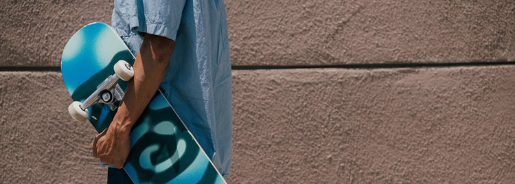 Lifestyle image of man holding a skateboard. 