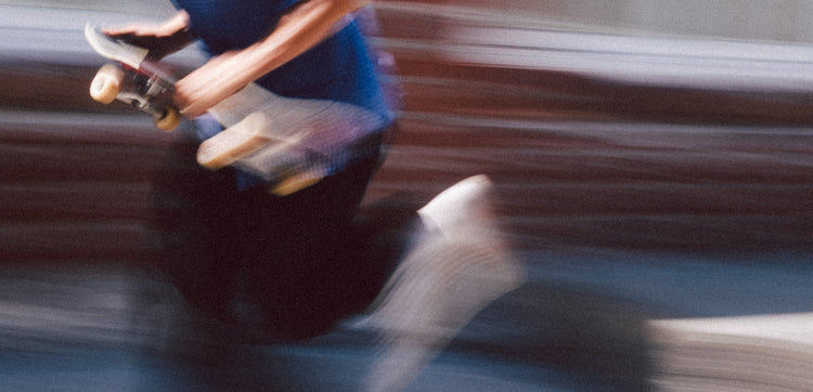 Action shot of Sammy running to throw skateboard down. 
