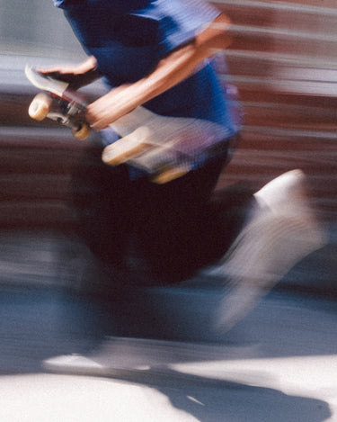 Action shot of Sammy running to throw skateboard down. 