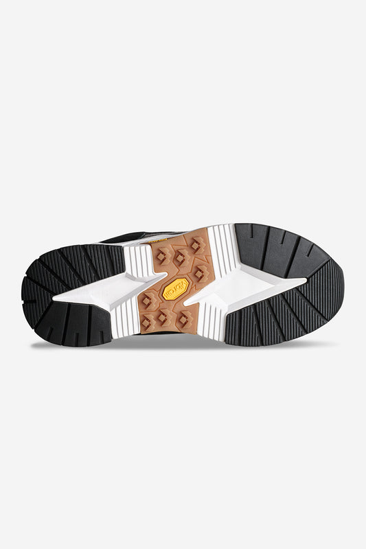 The image shows the outsole of the CT-4000 - Black/White, featuring black, white, and brown rubber sections with a yellow Vibram logo in the center. The angular tread provides traction atop a durable Vibram EVA sole.