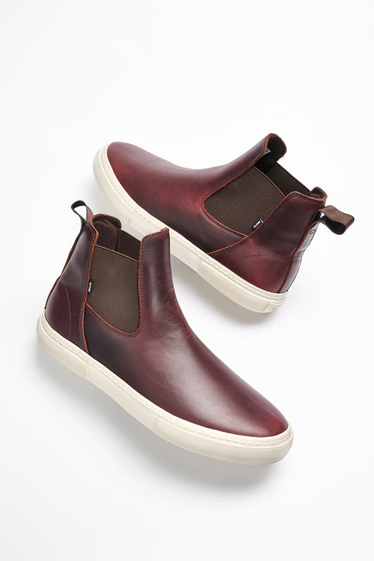 The Dover II - Oxblood features brown leather Chelsea boots with white rubber soles, brown elastic side panels, and pull tabs—combining timeless style with the comfort and grip of skate shoes, shown on a white background.