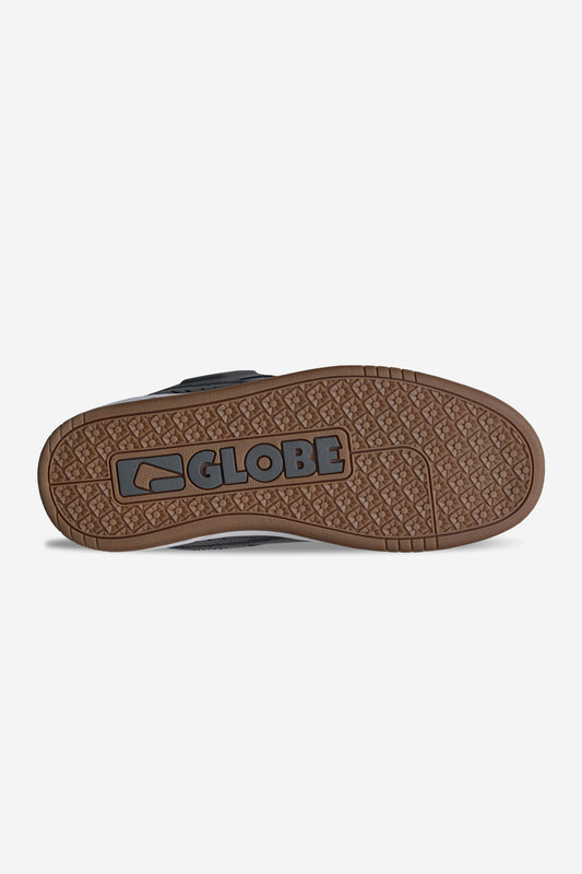 The image shows the brown rubber sole of the Globe Fusion - Charcoal/White skate shoe with GLOBE and its logo embossed in black. Geometric tread patterns offer grip, while a padded design ensures comfort for skating sessions.