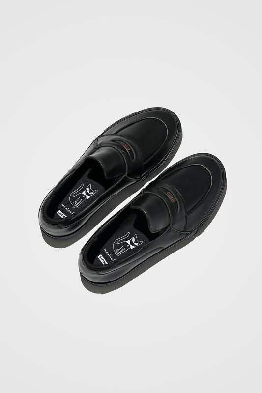 The Liaizon - Black/Maalouf slip-on loafers, shown from above, feature premium pull-up leather, rounded toes, cushioned insoles, and a white graphic cat illustration with text.