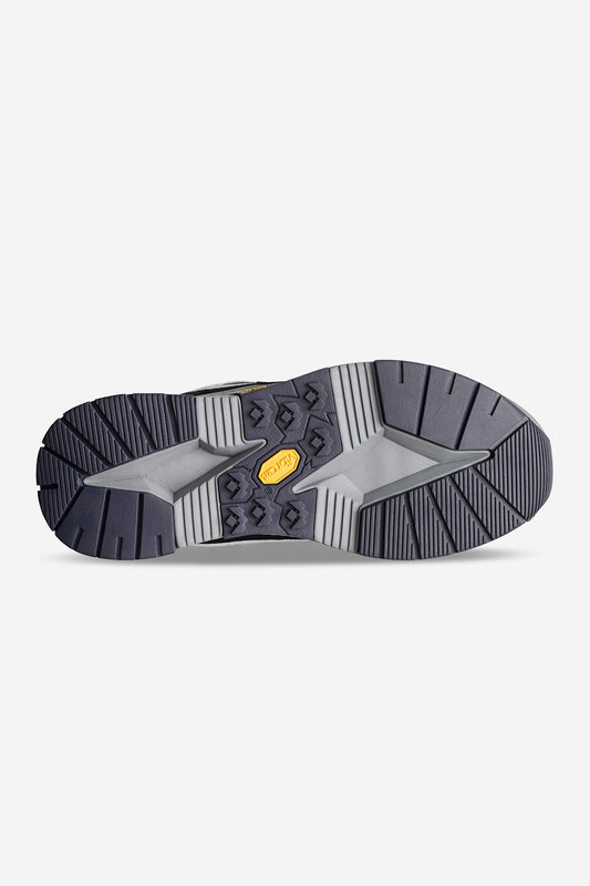 The image shows the bottom view of the RMS-3000 - Smoke/Black sneaker, featuring a dark gray tread pattern and a central gold Vibram label, with a durable Vibram EVA sole inspired by skate legends like Rodney Mullen.