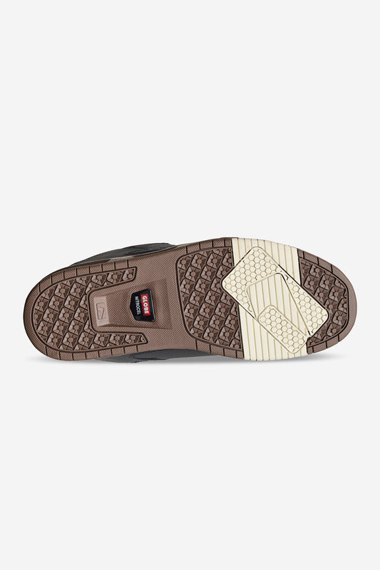 The image shows the Sabre - Lead/Gum shoe’s sole, featuring brown and beige geometric tread patterns for comfort and stability, with a red CAT logo at the center—blending heavy-duty durability with skate-inspired style.
