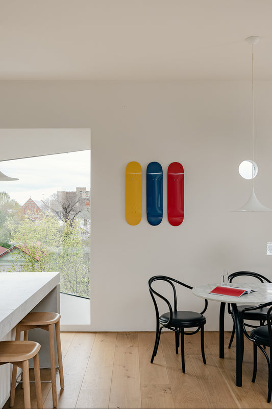 A dining room with a table and chairs, featuring a skateboard displayed on the wall using the Skateboard Deck Wall Hanger Accessories Hg 1sz" - White.
