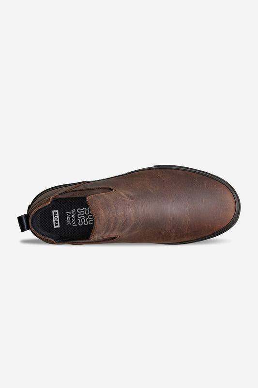 Dover II - Dark Brown/Wasted Talent: A brown leather slip-on Chelsea boot viewed from above, featuring a black elastic side panel, heel pull tab, black interior with visible insole label, rounded toe, and a subtly textured finish.