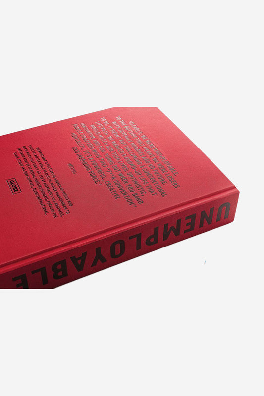 The Anniversary Book UNEMPLOYABLE - Version 2 RED is a red hardcover with bold black lettering on the spine and cover, referencing Globe International, the hardcore skate, street and surf company. Photographed against a white background.